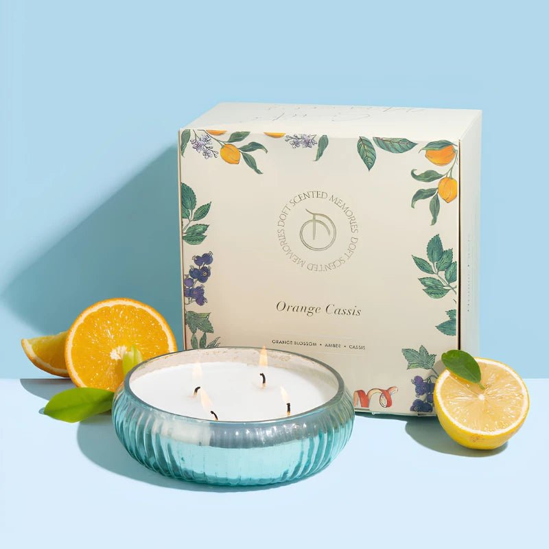 Mercury - Bowl Candle - Aqua - Orange Cassis, lit four-wick aqua glass bowl beside Orange Cassis box and citrus