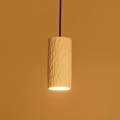 Cylindrical pendant light with textured design on a warm orange background