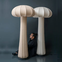 Person sitting between two large mushroom-shaped floor lamps against a dark background