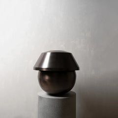 Modern black vase on a gray pedestal against a plain background