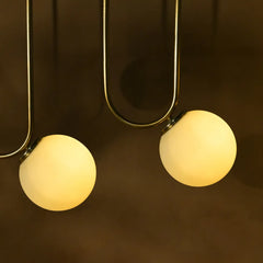 Two spherical light bulbs hanging from a gold fixture