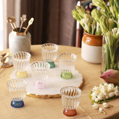Mini Twirl Bowl - Set of 6 – six fluted borosilicate glass bowls with solid colour bases on a marble board, tuberose vase behind