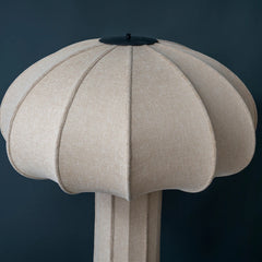 Beige umbrella shaped floor lamp with a handle against a dark blue background