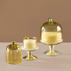 Decorative Sundance Aura Candle in Balmy Bergamot fragrance, Yellow color glass, lit small candle beside covered medium candle and loose cloche