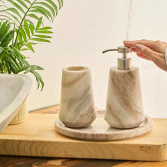 Otel Butterscotch Dispenser Set - Hand Reaching for Steel Pump on Bathroom Counter