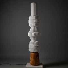 Paper Totem Floor Lamp -Tall, textured white sculpture on a wooden base against a dark background