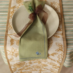 Rosabelle Chintz Ochre Table Runner with plate and green napkin tied with ribbon, top view