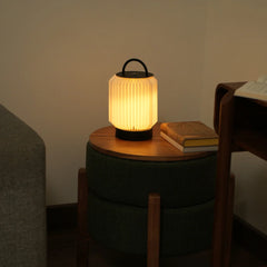 Tote Table Lamp with black metal handle and base on a wooden side table, warm light in a dimly lit room