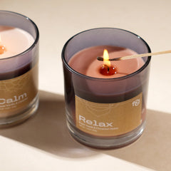Relax Apple & Cinnamon Vegan Wax Scented Candle lit by a match stick and placed with "Calm" scented candle