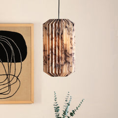 A paper origami lamp with a marble print hanging from the ceiling, displayed in a room next to a framed painting and a real plant.