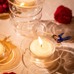 Decorative Glass tea light holder with intricately detailed bird design on the circular surfaces with lit candle