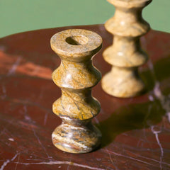 Two Astra Brown Marble Candle holders on a textured surface with a green background