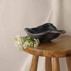 Black kai ceramic bowl on a wooden stool with white flowers