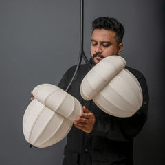 Acorns Pendant Lamp showing man holding two large, white, spherical lampshades, hanging on black metal rod