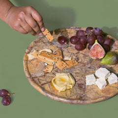 Platter with crackers, figs, grapes, and feta cheese on a green background