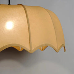 Close up of a ceiling light with beige lampshade on a plain background