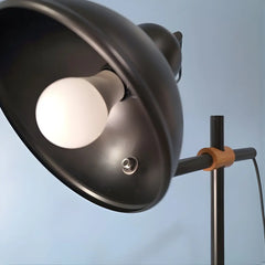 Modern floor lamp close-up of the black metal shade in dome shape and brown wooden accent