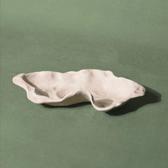 Wavy Kai Organic ceramic dish on a green background 