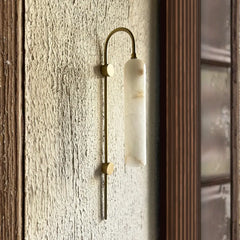 Lune Rise Alabaster Wall Light with marble-like finish on a textured wall.