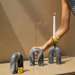 Three grey U-shaped candle holders, each featuring a unique pattern