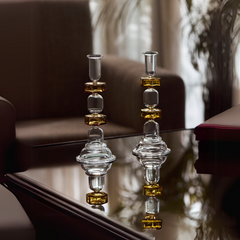 Two kanak candle stands with a yellow tint, with a tapered shape, displayed in a living room.