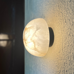 Side angle of Alabaster Wall sconce Warm White glowing on a textured wall