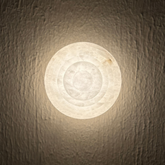 Skive Wall Sconce, close view of round light fixture on a textured wall