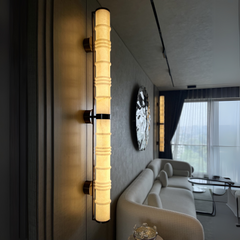 Alabaster Wall Sconce with marble tube casting warm LED light mounted on wall in modern interior setup