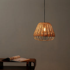 Woven pendant light hanging against a plain wall with a table and book in the foreground.
