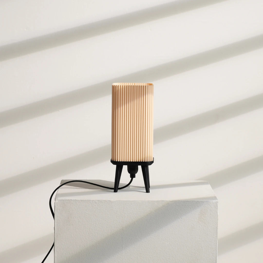 Modern Table Lamp with ribbed design on a white pedestal against a white wall.