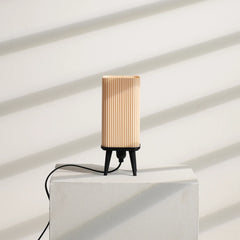 Modern Table Lamp with ribbed design on a white pedestal against a white wall.