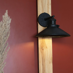 Leatherette Wall Lamp in Black, wall-mounted light fixture on a wooden post against a red wall.