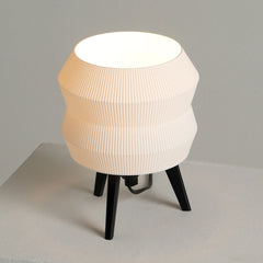 Small Echo table lamp with a ribbed beige shade and black legs on a neutral background