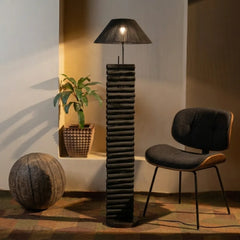 Modern floor lamp with textured design in a room setting with a chair and plant.