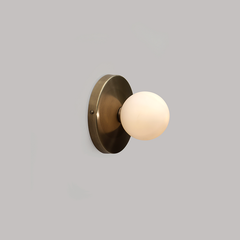 Side profile of Dew Wall Sconce , brass backplate with frosted globe diffuser mounted on wall