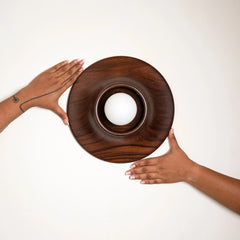 Two hands holding a wooden Paten Wall Light