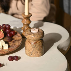 Marble tea light candle holder with a lit candle on a table with fruit plate