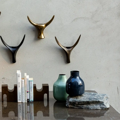 Decorative Vases made of iron placed on a table with wall art and antler shapes on a textured wall, books