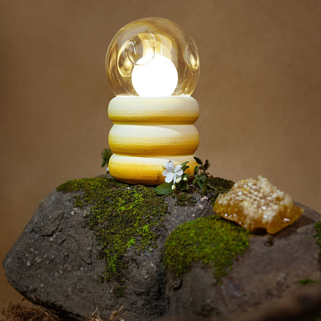 Unique Honey Lume Table Lamp with light bulb on a rock with a natural background