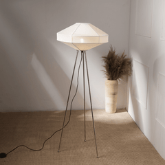 A contemporary silver nickel floor lamp with a geometric fabric shade, placed in a room