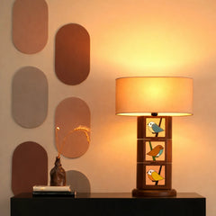 Decorative table lamp with bird designs on a wooden base in a warm-toned room.