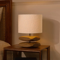 Unique Sabbia Table Lamp with a textured fabric shade & wooden base on a side table against a neutral wall.