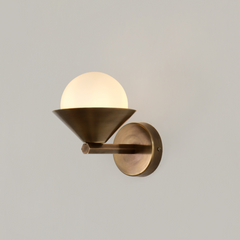 A handcrafted cone wall sconce made of brass with a spherical light cover and with visible mounting plate