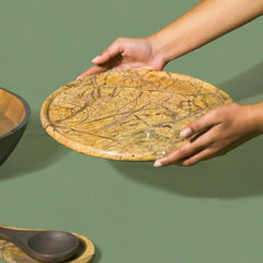 Person holding a leaf-patterned ceramic plate on a green background
