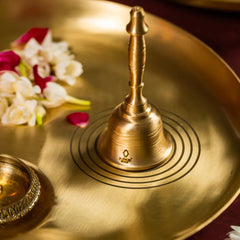 Brass bell on a brass plate with flowers in the background
