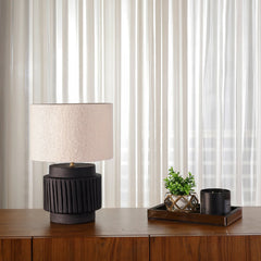 Decorative Albe Table Lamp with black terracotta base and boucle lampshade placed on a wooden surface 
