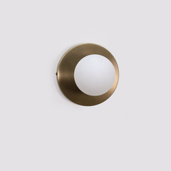 Detail of Dew Wall Sconce in aged brass finish with frosted glass shade and clean circular design