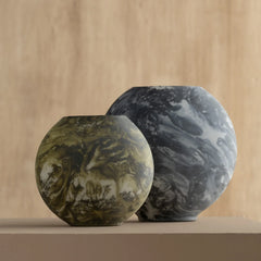 Two marbled glass bella vases on a wooden surface with a wooden background