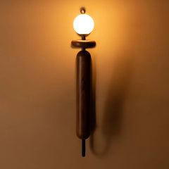 Dash & Dot Wall Sconce with wooden base and white bulb casting warm light