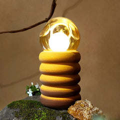 Ceramic Honey Lume Table Lamp with a textured base and clear glass shade on a natural background